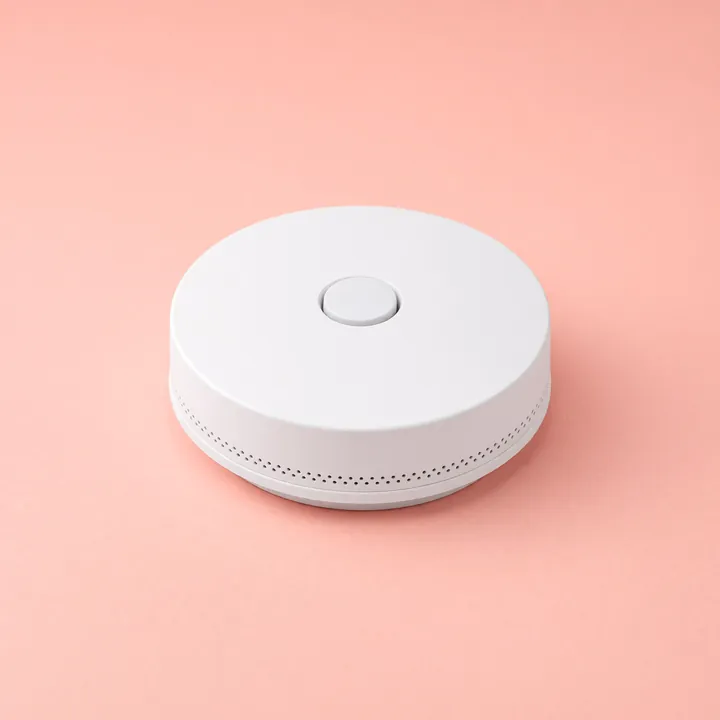 Round white photoelectric smoke alarm with a center test button